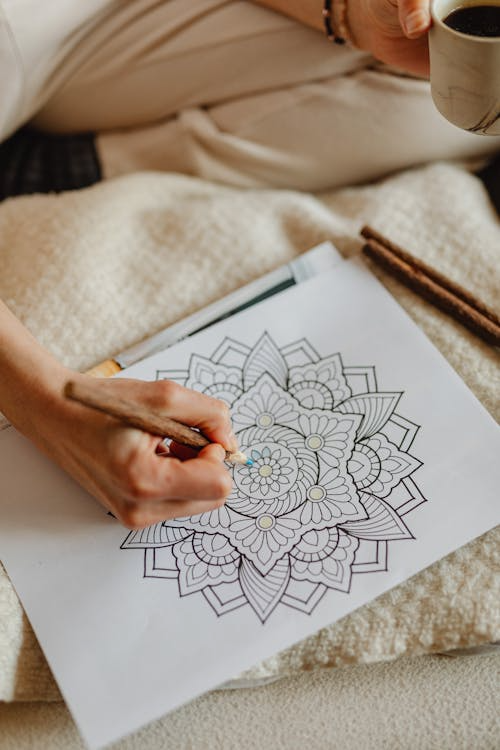 Close-up of hands coloring an intricate mandala design